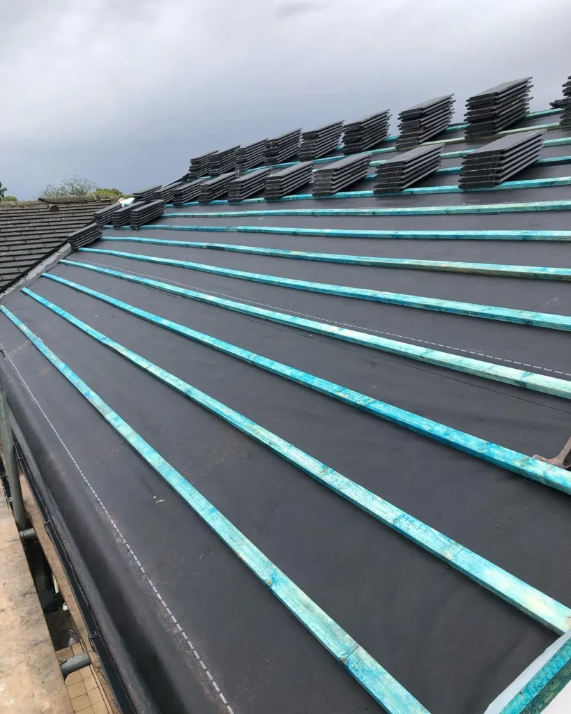 Pitched roof with underlay and battens laid and stacks of tiles ready to fit